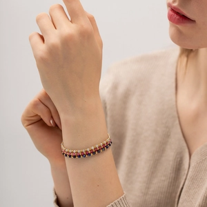 Detail of multi-layer beaded bracelets with gold accents and colorful gemstones on wrist
