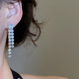 Close-up of silver tassel earrings with square zircons on model for luxury style