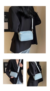 Detail of light blue PU leather crossbody bag with wide patterned strap and gold hardware