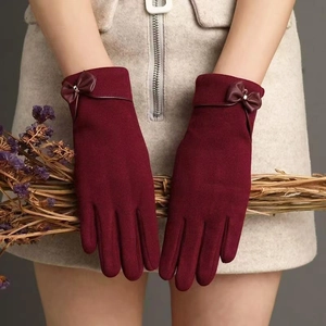 Detailed close-up of wine red gloves with bow tie decor holding dried flowers