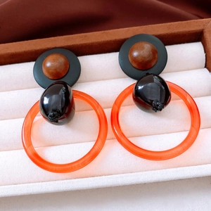 Close-up of geometric earrings with resin wood beads and orange acrylic ring design