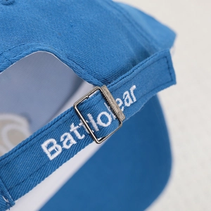 Detail of adjustable metal buckle and white letter embroidery on blue cotton baby cap