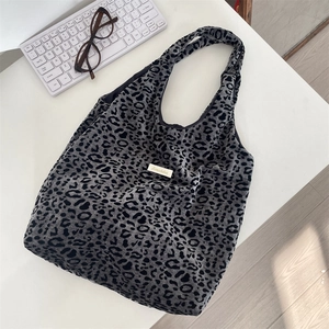 Detail of grey leopard print canvas tote with brand label, eyeglasses and keyboard