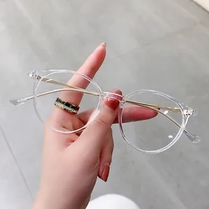 Retro round transparent blue light glasses with slim gold metal temples held by hand