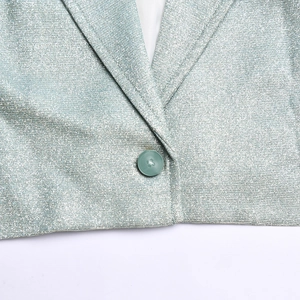 Détail d'un blazer argenté scintillant montrant le revers cranté et le bouton unique