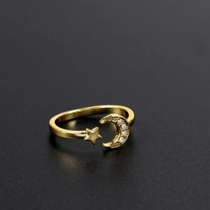 Macro shot of gold crescent moon and star ring with sparkling crystals on black background