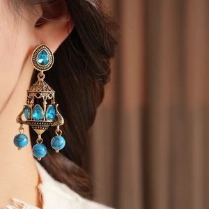 Detail of vintage gold chandelier earrings with blue stones and intricate filigree work