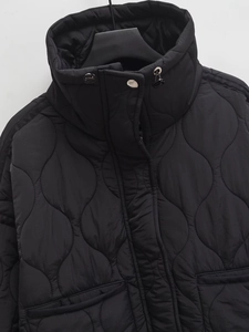 Detail of black water ripple quilted jacket featuring a stand collar and drawstring hem