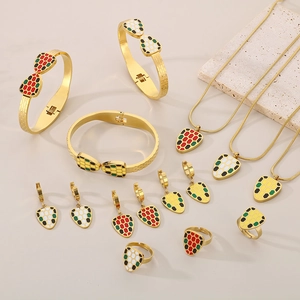 Flat lay of gold snake-themed jewelry set with colorful enamel scales and gemstone details
