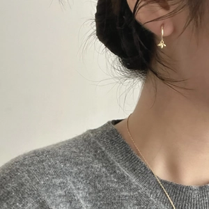 Detailed view of a gold bee pendant earring and matching necklace on a female model