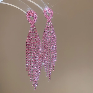 Detail view of pink rhinestone tassel earrings with sparkling crystals on a warm background