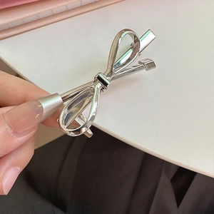 Minimalist silver bow metal hair clip in a french elegant style held in hand