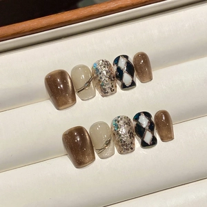 Detail of brown checkerboard and cat-eye handmade press-on nails on a jewelry display tray