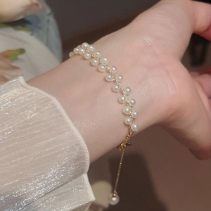 Gros plan d'un bracelet de perles à double rangée avec chaîne en or et soie