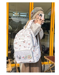 Detailed close-up of white dachshund graffiti backpack with mesh front and decorative pins
