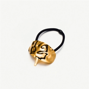 Detail of gold hammered metal hair tie with black elastic band and buckle closure