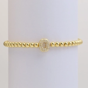 Macro shot of gold beaded bracelet with an oval charm set with sparkling cubic zirconia