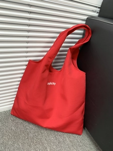 Detail of red canvas tote bag with Simplicity print and wide shoulder strap