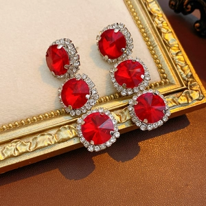 Detailansicht von königlichen Ohrringen mit roten Edelsteinen auf goldenem Ornamentrahmen