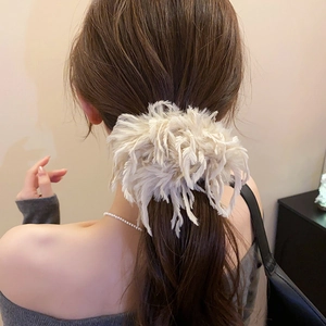 Gros plan d'un grand chouchou en plumes duveteuses blanc crème sur cheveux bruns