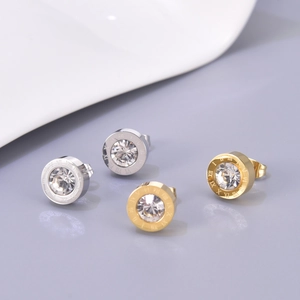Gros plan de boucles d'oreilles argentées et dorées avec chiffres romains et zircon