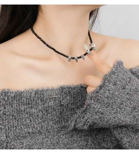 Detail of gothic black beaded choker featuring silver skull pendants on model