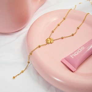 Détails macro du collier trèfle doré avec incrustations de zircons et chaîne à billes