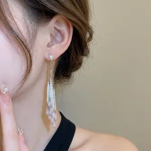Élégantes boucles d'oreilles argentées avec pompon en cristal rose portées par modèle
