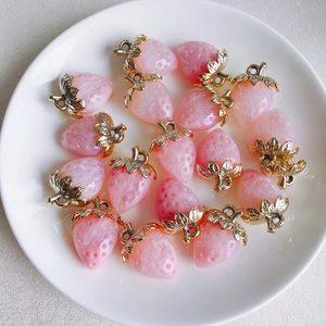 Detailed view of pink resin strawberry charms with gold leaves and glitter finish