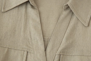 Detail of V-neckline on light khaki linen-style sleeveless maxi dress with visible textures