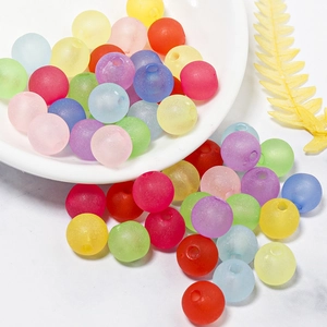 Macro shot of colorful matte acrylic beads spilling on a white marble surface