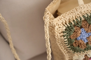 Macro detail of hand-crocheted shoulder strap texture on a floral straw beach bag