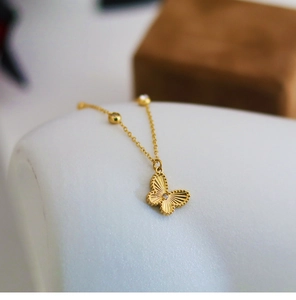 Detail of golden butterfly pendant with radial textures and small crystal accents