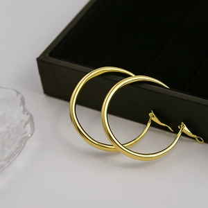 Macro shot of polished gold hoop earrings resting on a black jewelry presentation box