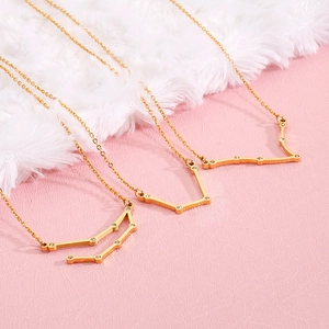 Close-up of three gold zodiac necklaces with tiny crystals on a soft plush background