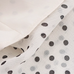 Macro shot of breathable white chiffon fabric with black polka dots for summer dress
