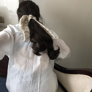 Elegant beige silk scarf with black polka dots worn as a ponytail hair accessory for men