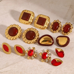 Vintage gold and red agate earrings set with zircon accents on a marble background