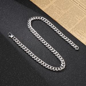 Close-up of silver Cuban chain necklace on black textured surface with classic link detail