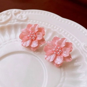 Macro detail of pink floral resin earrings with delicate petal textures and pearl centers