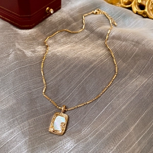 Close-up of vintage gold plated square necklace with white mother of pearl inlay