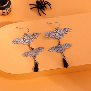 Silver hollow bat earrings with black teardrop beads on a festive orange background
