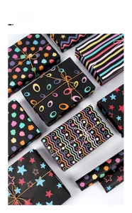 Detail view of black gift wrapping paper featuring colorful geometric patterns and stars