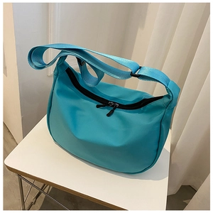 Detail of bright blue nylon crescent crossbody bag with black zipper and wide strap