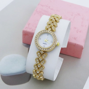 Elegant gold ladies bracelet watch with sparkling rhinestones on a white display stand
