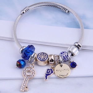 Stainless steel cable bracelet with blue crystal beads and key pendant on marble stand