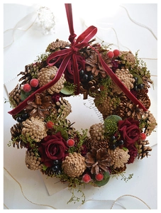 Close-up of vintage Christmas wreath with red roses, pine cones, and velvet ribbon