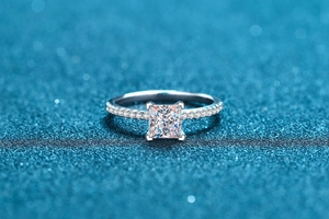 Macro view of princess cut moissanite ring with micro-pave setting on blue background