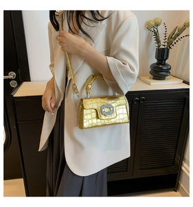 Détail du sac doré texture crocodile avec boucle en cristal porté avec un blazer beige