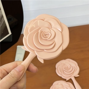 Detail von rosa Handspiegeln in Rosenform mit 3D-Textur auf einer Holzoberfläche